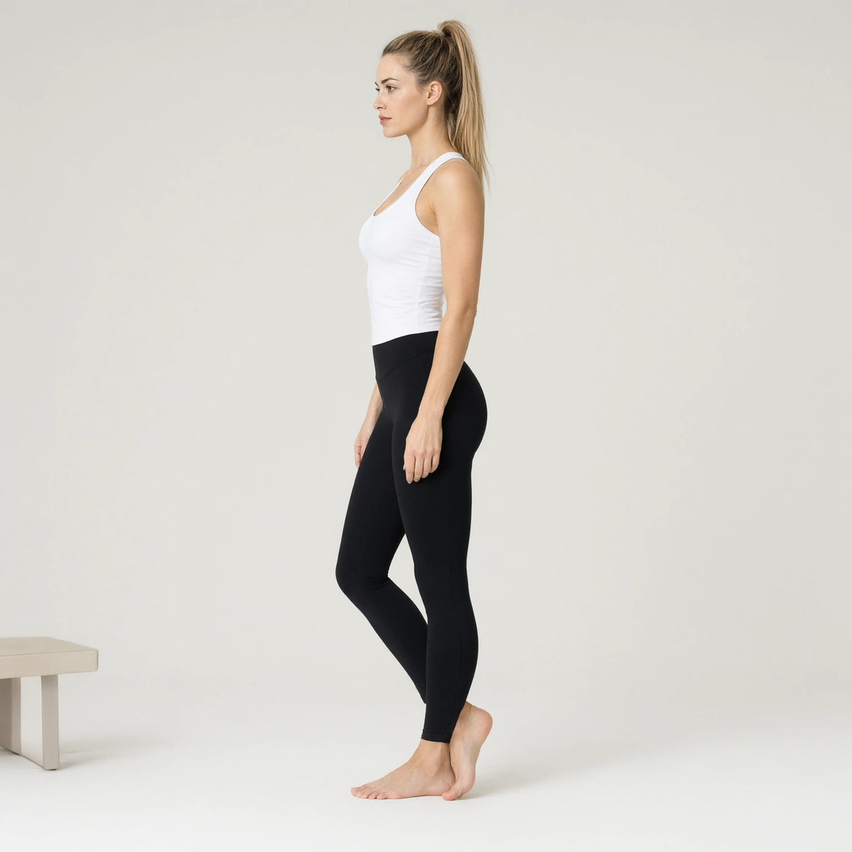 White | Fisoew Workout Tank Tops Sleeveless Scoop Neck Racerback｜DUVETMOON – side view (ankles gently crossed)