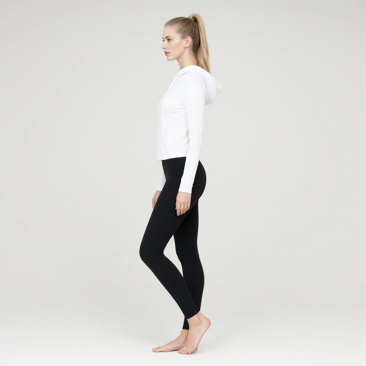 White | Long Sleeve Hooded Yoga Top｜DUVETMOON – side view (ankles gently crossed)